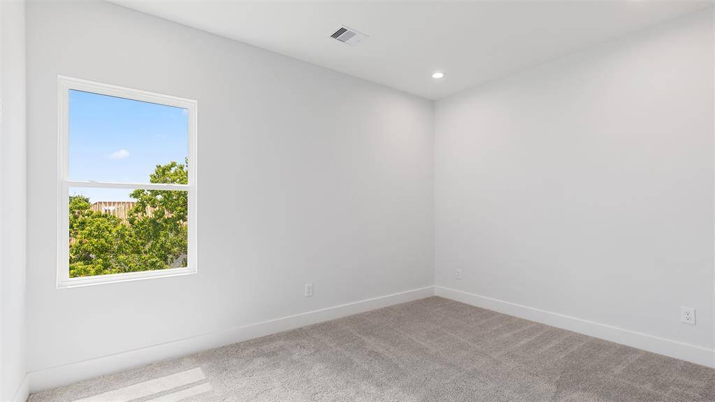 Secondary bedroom features awindow and plush carpet.