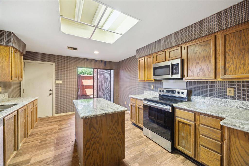 Sunny & bright island kitchen with granite counter tops &le storage with a small patio off the breakfast area.