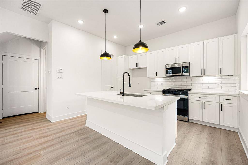 This kitchen is a chef’s dream, blending elegance with functionality! Soaring ceilings and bright white cabinetry create an open, airy feel, while stunning Quartz countertops and a sleek subway tile backsplash add a touch of modern sophistication. Stainless steel appliances, recessed lighting, and custom pendant fixtures elevate the space, making it as beautiful as it is practical. The oversized Quartz island, complete with a double sink and breakfast bar seating, is perfect for entertaining.