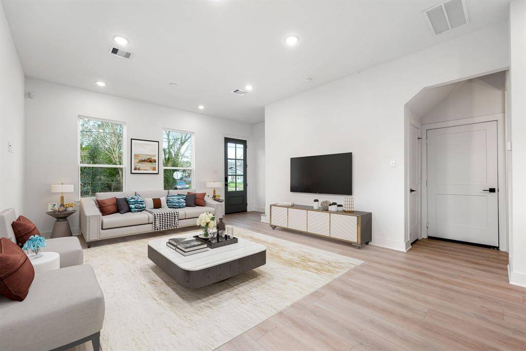 Light wood flooring adds warmth and sophistication, while the glass-paneled door invites guests and family to experience contemporary living at its finest in this beautifully crafted home!