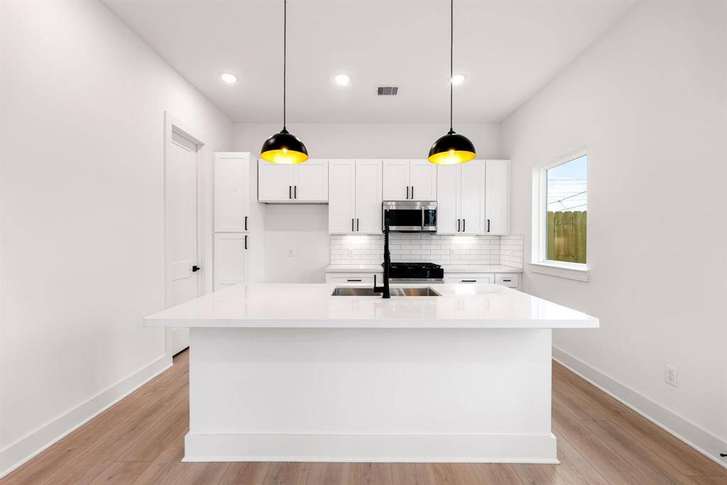 This kitchen is a chef’s dream, blending elegance with functionality! Soaring ceilings and bright white cabinetry create an open, airy feel, while stunning Quartz countertops and a sleek subway tile backsplash add a touch of modern sophistication. Stainless steel appliances, recessed lighting, and custom pendant fixtures elevate the space, making it as beautiful as it is practical. The oversized Quartz island, complete with a double sink and breakfast bar seating, is perfect for entertaining.