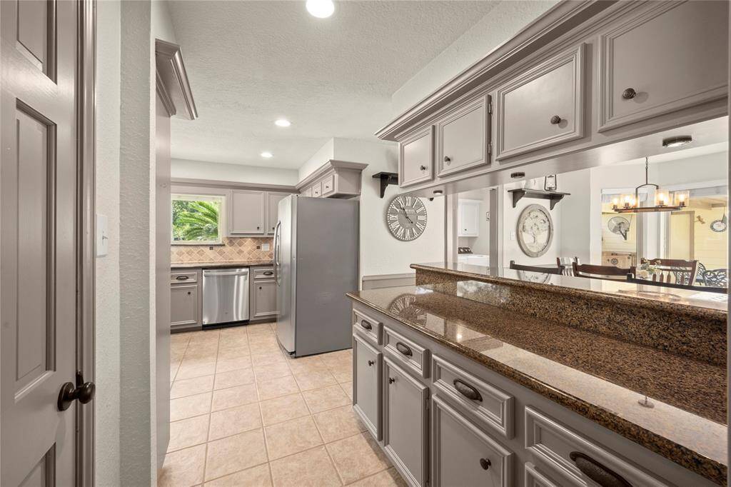 From the dining room, you enter this extended kitchen with a huge amount of counter space, a breakfast bar and an amazing amount of storage above and below the granite countertops.  To the left, behind the door is the huge walk-in pantry.