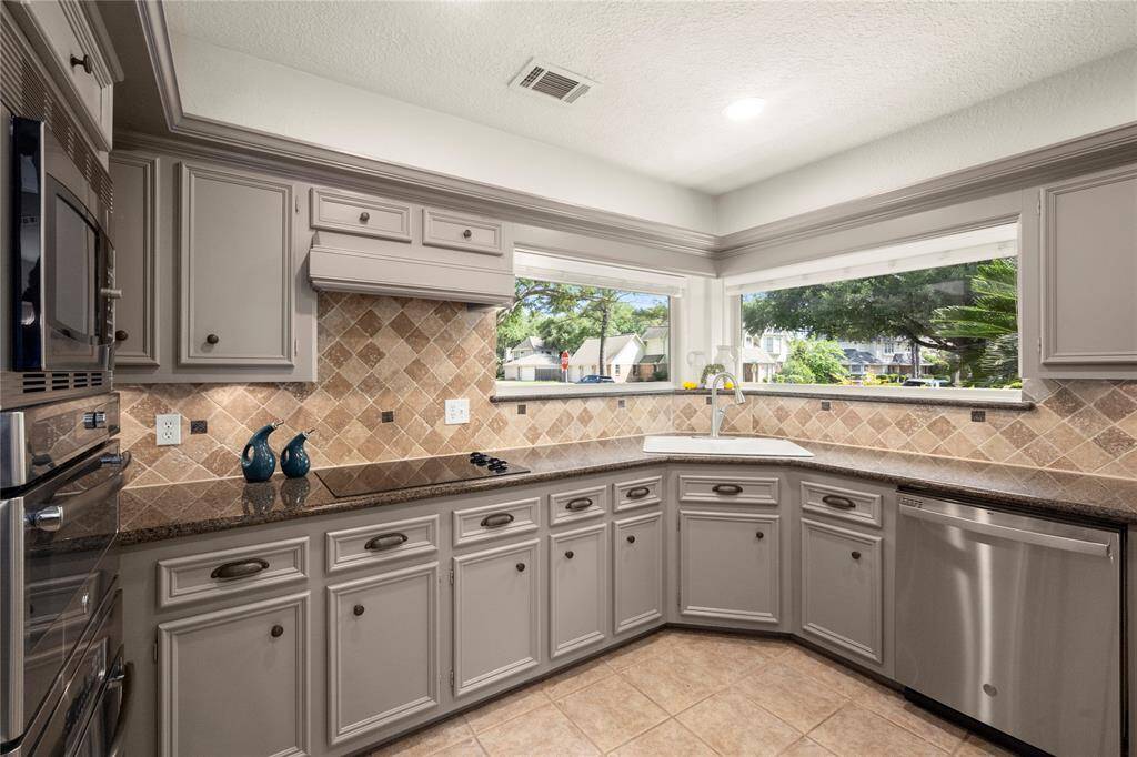 Every part of this spotless kitchen literally glistens as the sunlight streams through those amazing windows and hits every surface. This view shows how much counterspace is available around the double porcelain sink and above the stainless steel dishwasher.
