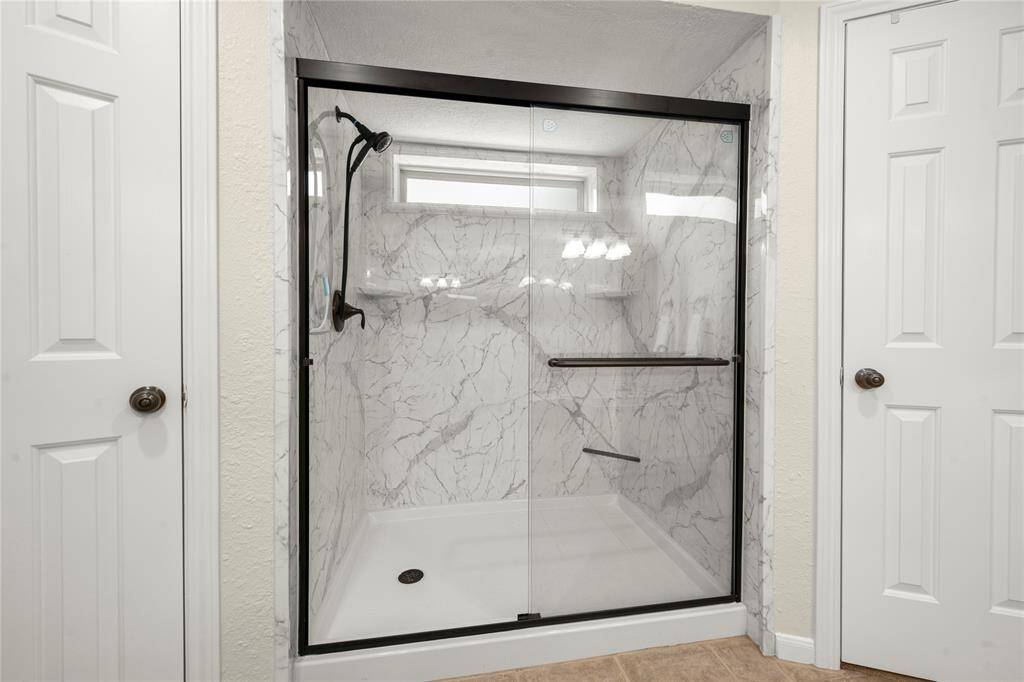 This handsomely remodeled walk-in shower also has a privacy window that allows light into the shower while mantianing your privacy.  Two spacious walk-in closets are on either side of this massive shower.