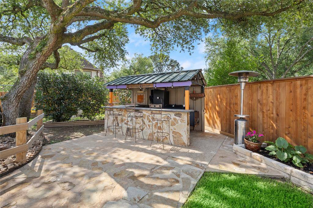 Shaded under this sprawling oak's branches is a hill country style outdoor bar and cook house just waiting for your smoker and/or grill! Constructed of concrete blocks, flagstone, wood and metal roof, this "bar and grill" is made to last!