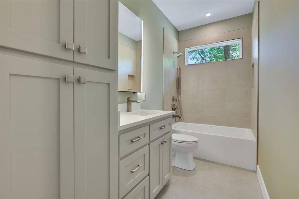 Stylish guest bathroom featuring a deep soaking tub, custom cabinetry and a hand-held shower