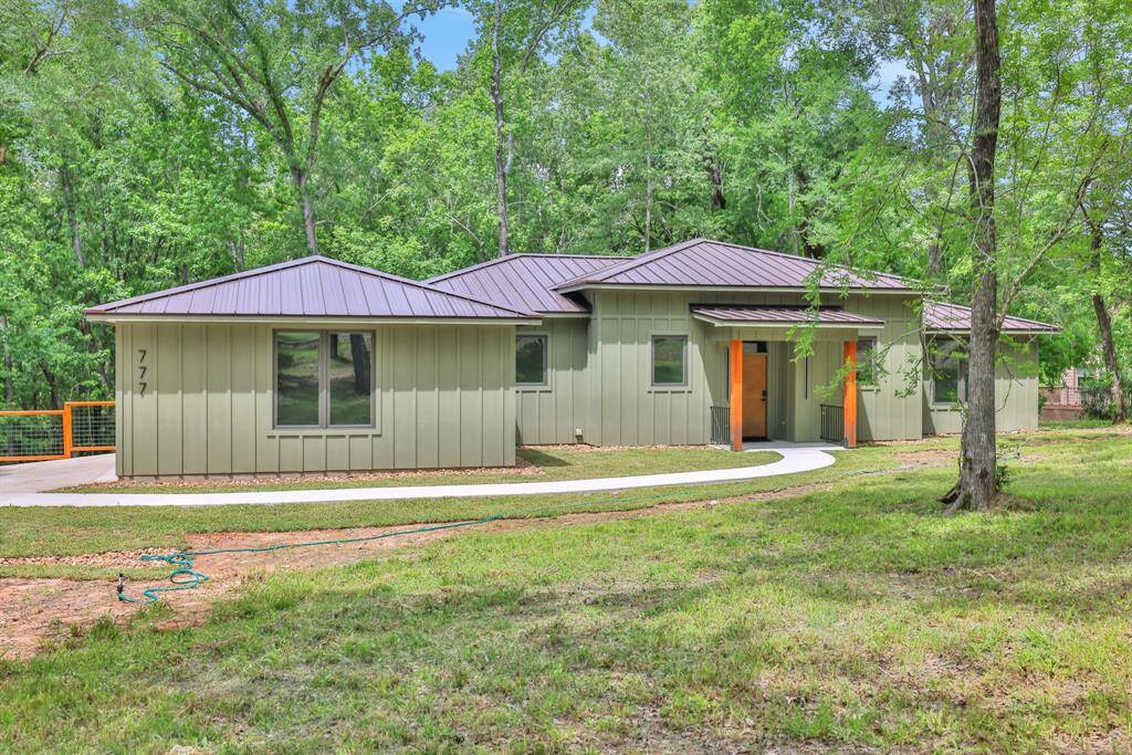 Striking front entry with warm wood accents and a welcoming modern aesthetic—tucked beneath a canopy of trees.