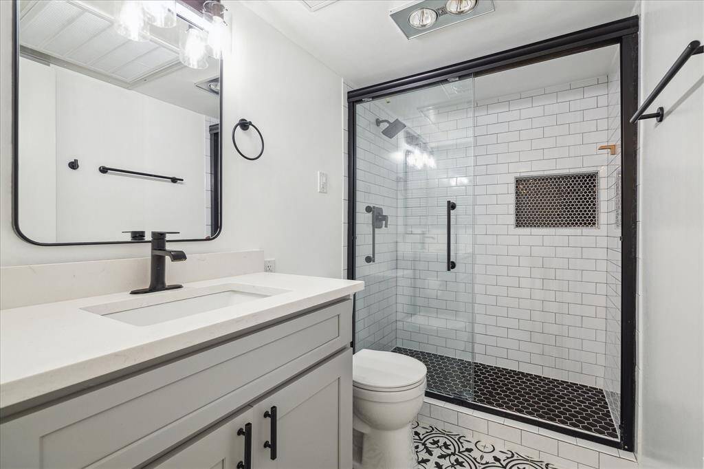 The full bath is located upstairs, conveniently between bedrooms. It received a complete renovation in 2021 with new plumbing, walk-in shower, stylish vanity with quartz countertops, tile, and hardware.