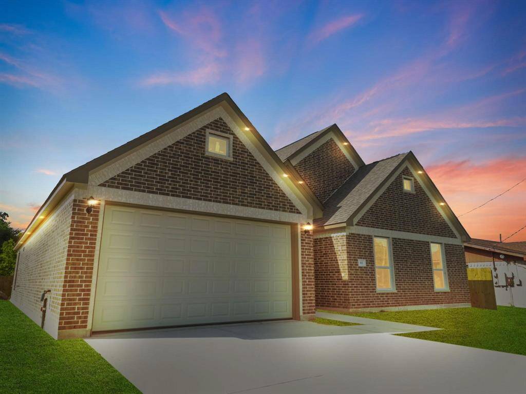 This brick home features outdoor under lighting around soffits, showcases its beauty at night.