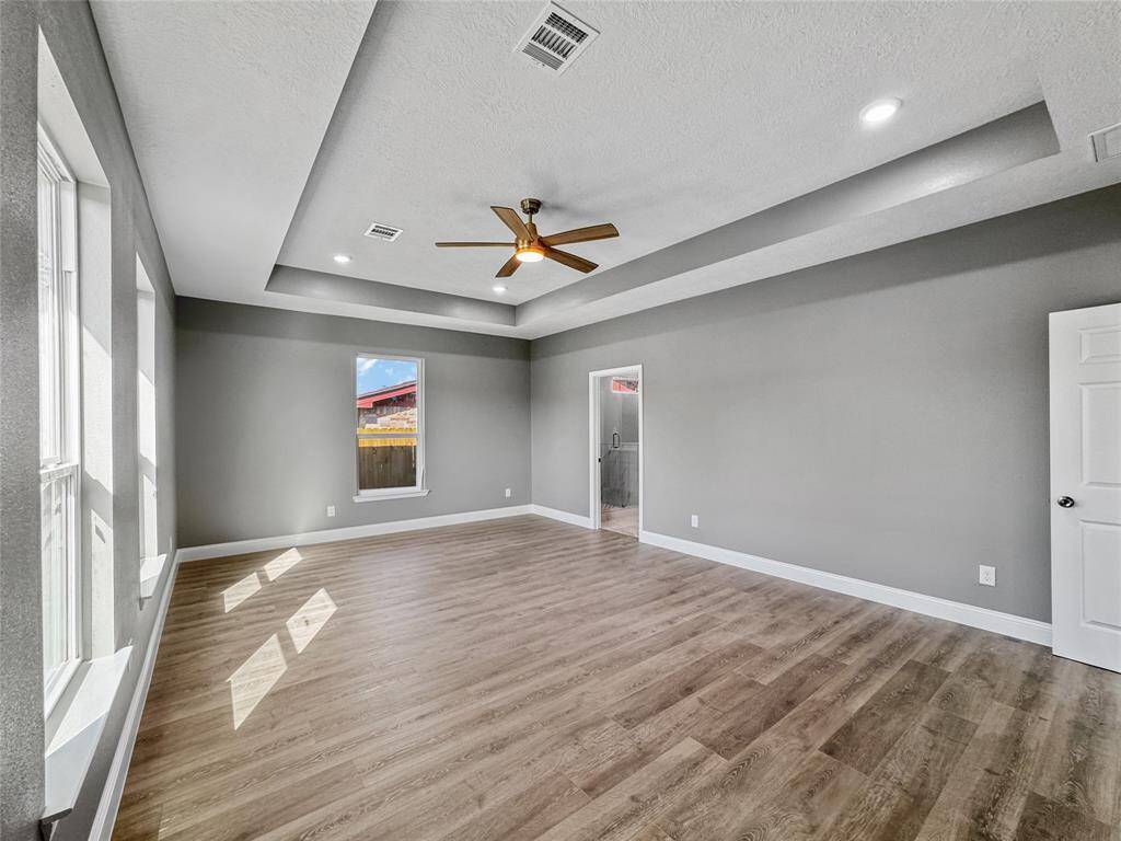 Another view of the primary bedroom, spacious enough for a sitting area, tray ceiling features recessed lighting.