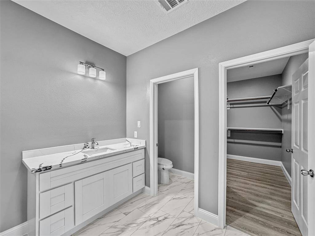 Quartz countertops and ceramic tile continue into  the primary bath.