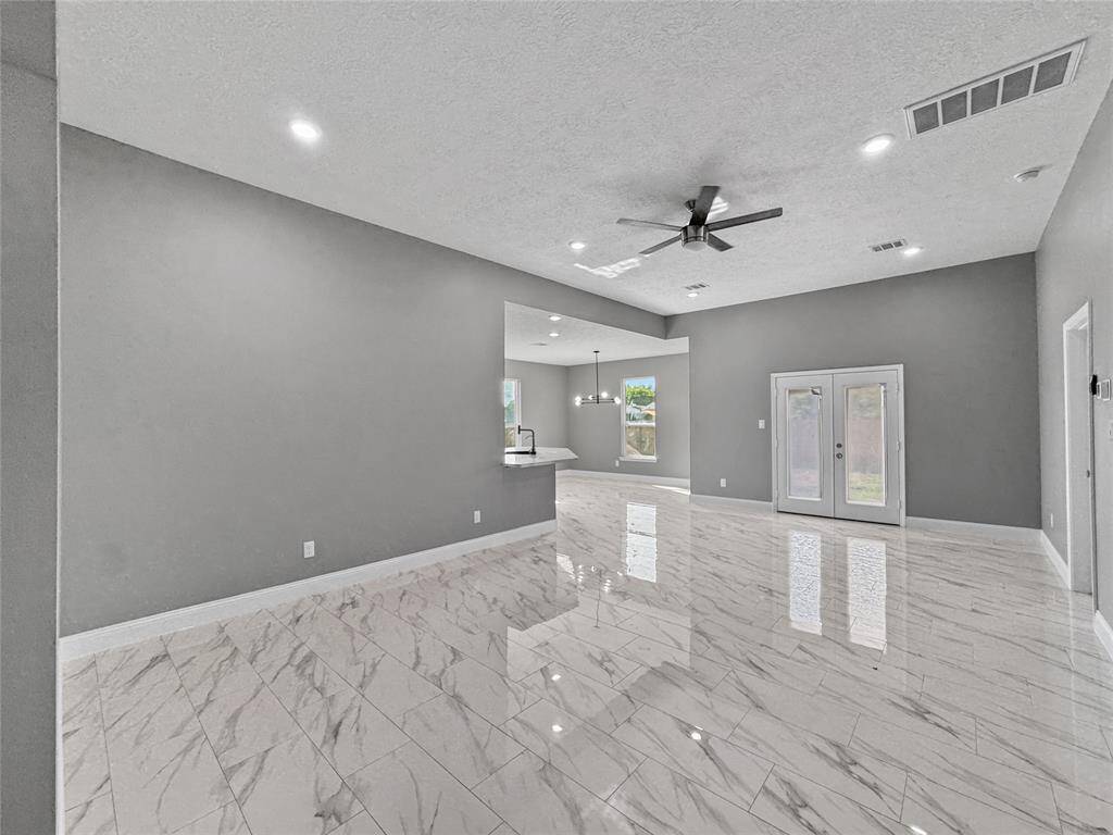 Step into this elegant and open living room with soaring 10 ft ceilings throughout entire home. Featuring rich porcelain tile. Recessed lights and ceiling fans included. French doors lead you to back yard.