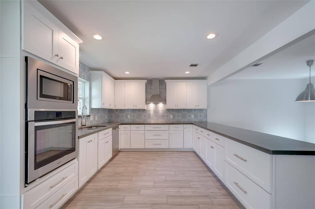 Modern and bright kitchen with breathtaking huge quartz countertops and stainless steel appliances.