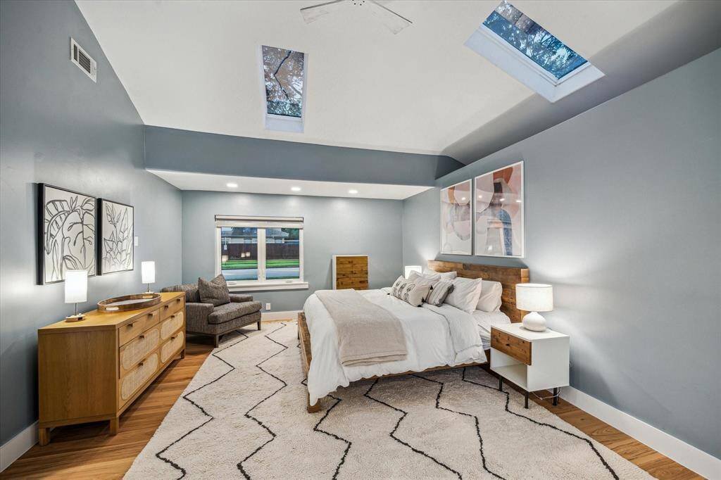 Spacious serene primary bedroom with tall ceilings, elegant warm hardwoods, great window with motorized shade and nicely sized walk-in closet.