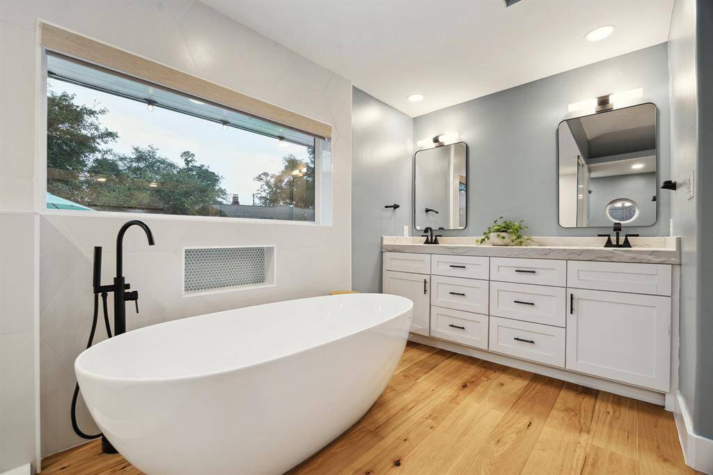 Experience luxury in the open spa-like primary bathroom, featuring a double vanity with quartz counters, ample storage, and a window with custom shade offering serene backyard views with additional natural light.