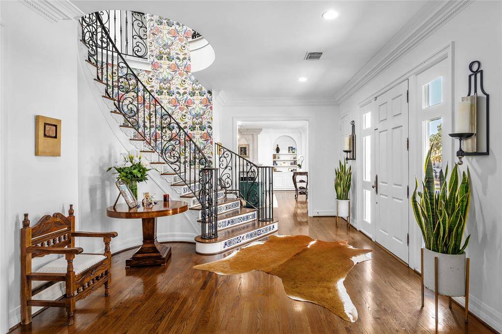 Graceful curved staircase with designer tile and designer wallpaper in gracious foyer with open entry to large formal dining room and living room