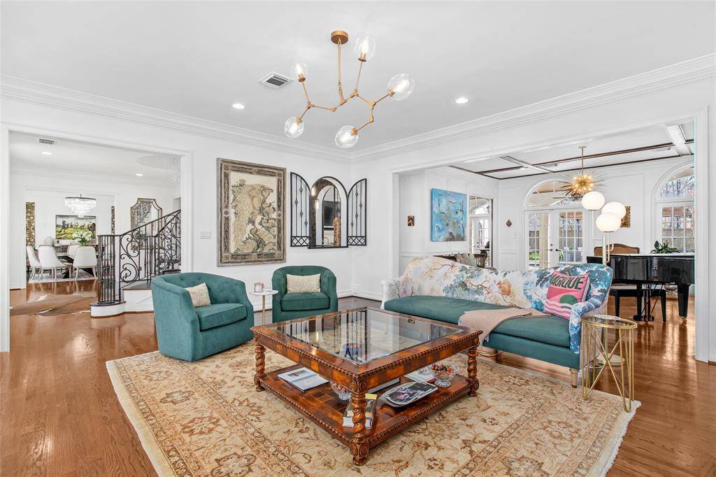 Elegantly appointed formal living room features custom carved limestone fireplace, high ceilings, crown molding, built ins with directional lighting, two arched windows and recessed lighting