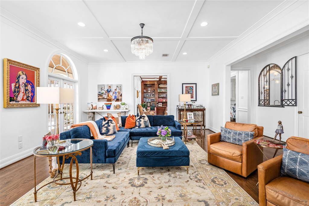 Spacious family room has a custom carved limestone fireplace, beautiful molding, cross-beamed ceilings and double palladium French doors that look out to the beautiful pool and landscaping