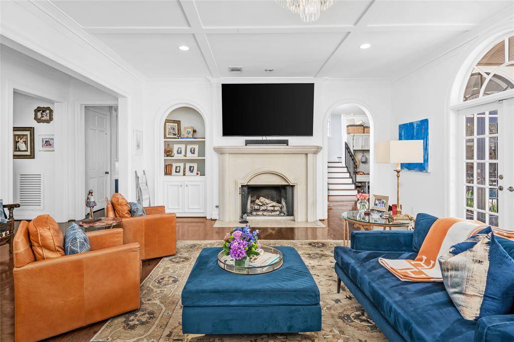 Spacious family room has a custom carved limestone fireplace, beautiful molding, cross-beamed ceilings and double palladium French doors that look out to the beautiful pool and landscaping