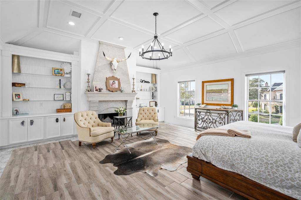 Sophisticated primary retreat has custom-carved limestone fireplace flanked by built-in shelves. Controlled, recessed lighting in elevated ceiling and was fully remodeled in 2022.