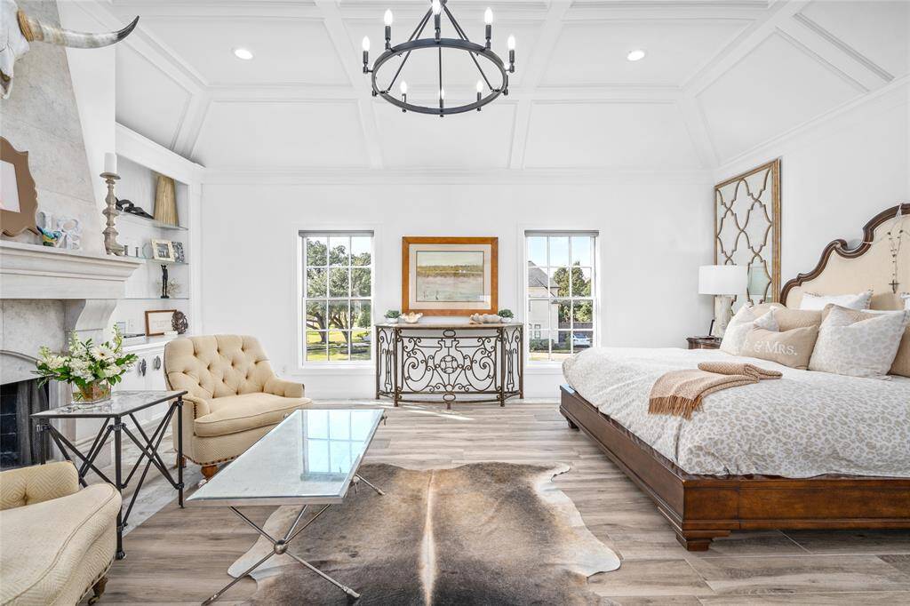Sophisticated primary retreat has custom-carved limestone fireplace flanked by built-in shelves. Controlled, recessed lighting in elevated ceiling and was fully remodeled in 2022.