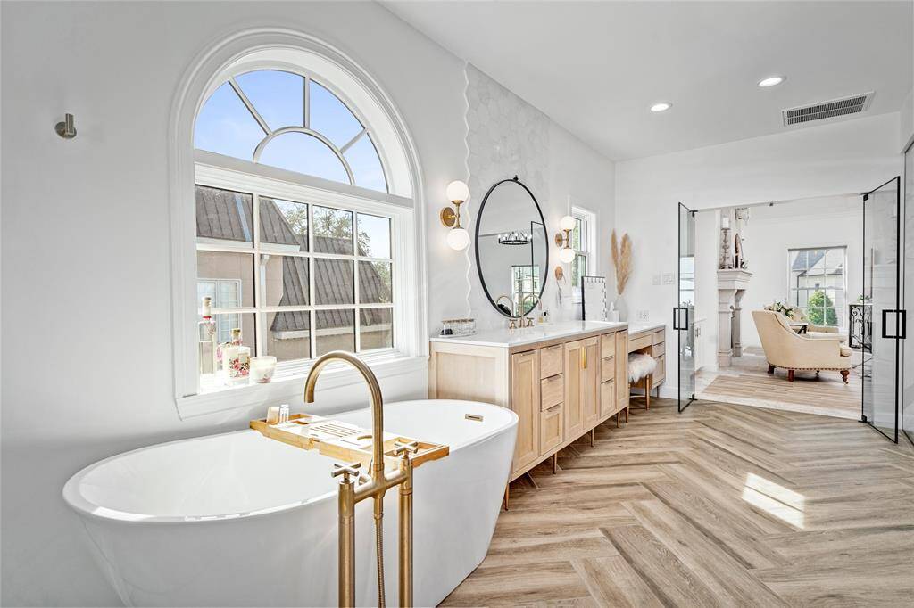Primary bathroom oasis with heated floors, glass door entry, double vanity areas, soaking tub, and large separate shower, and abundant storage
