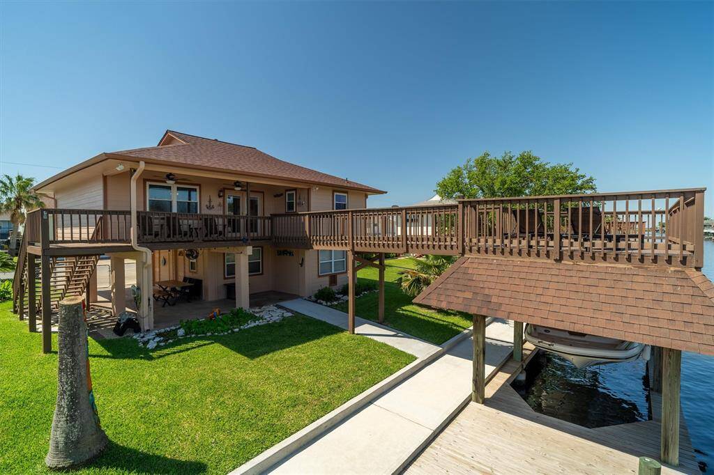 Waterside of home showcasing the boathouse/upper party deck, and beautiful yard