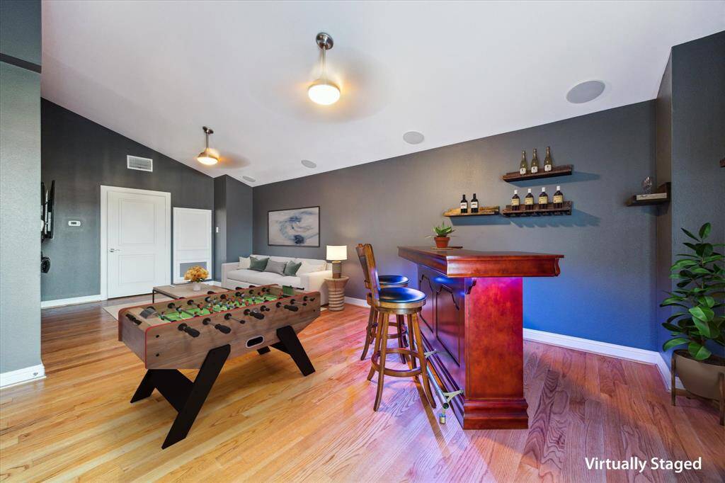 Fourth floor: The expansive game room offers incredible versatility, easily accommodating multiple uses—from a media lounge to a home office or fitness area. It features beautiful hardwood floors, soaring ceilings, and built-in speakers for an immersive experience. Flooded with natural light, this impressive space connects directly to both large rooftop terraces, making it ideal for entertaining or relaxing indoors and out.