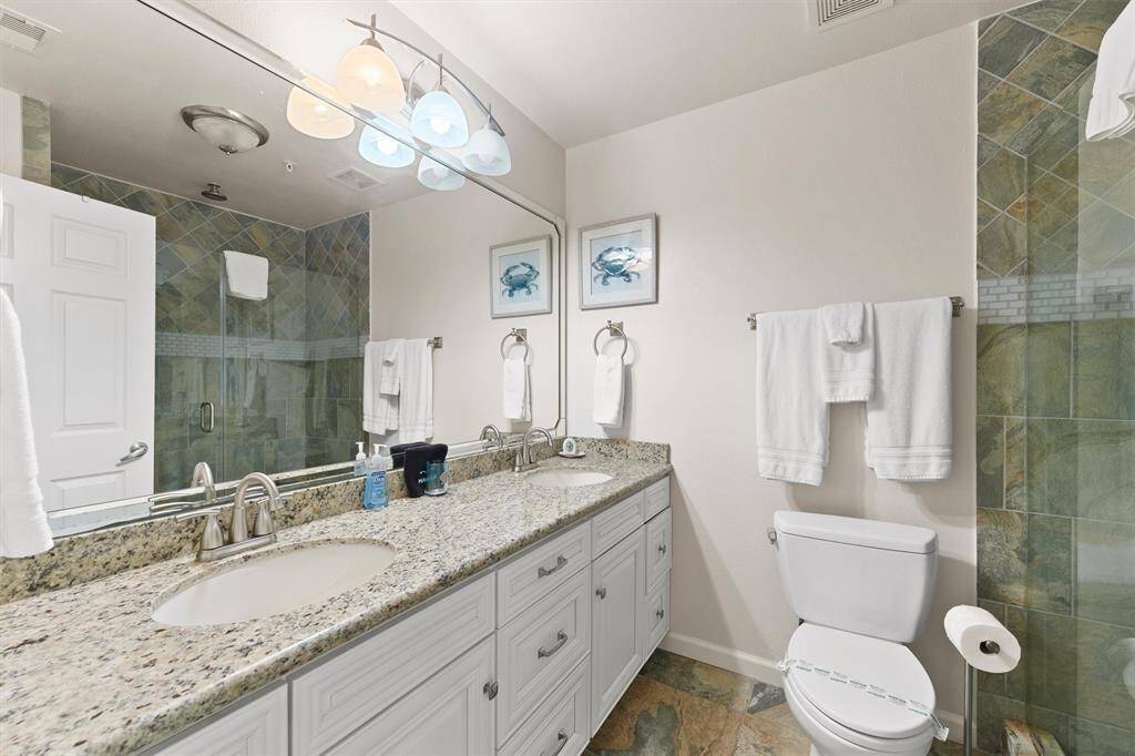 The spa-like primary bathroom features a granite double vanity and a beautifully tiled walk-in shower with glass doors.