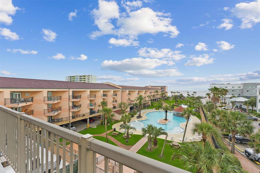 Enjoy a resort-style perspective with a scenic view of the lush tropical grounds, sparkling pool, and beachfront horizon.