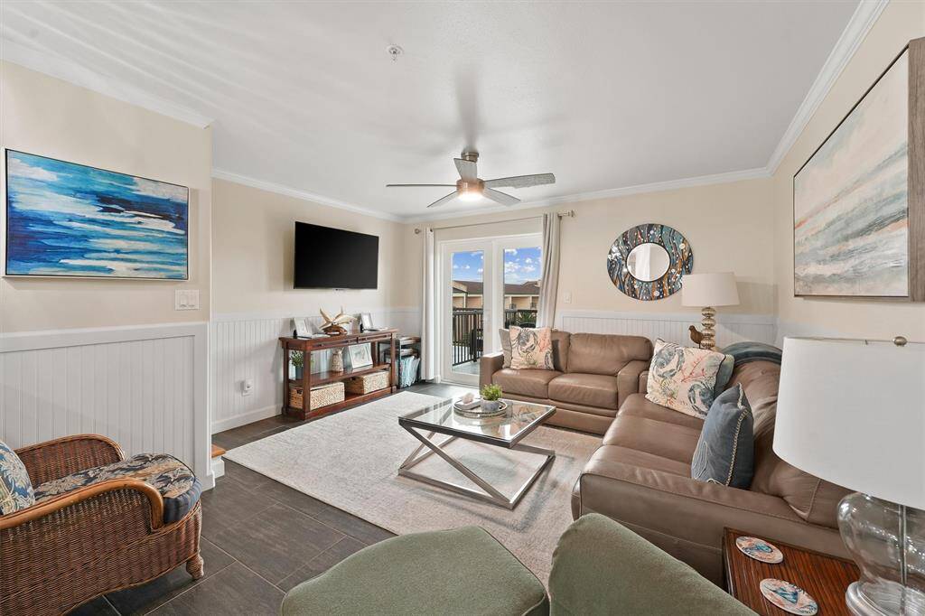 The inviting living room features coastal charm, comfortable seating, and direct access to the private balcony with ocean views.