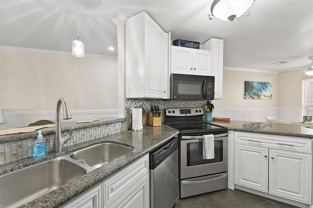 The updated kitchen showcases granite counters, a double sink, and a stylish tile backsplash for a polished finish.