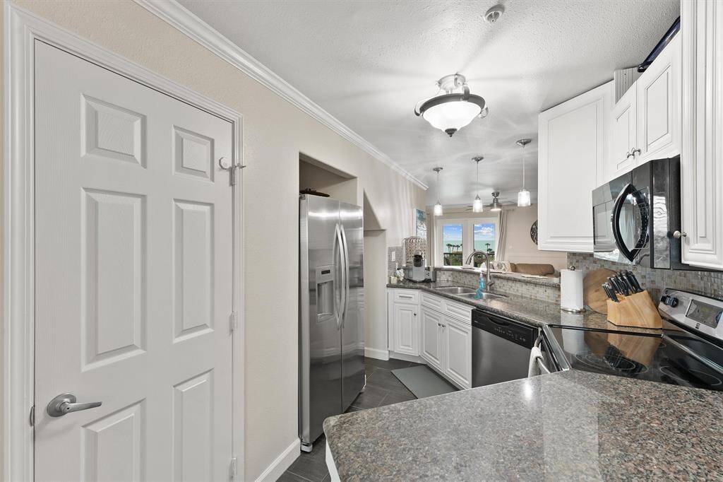 A well-appointed kitchen with white cabinetry, stainless steel appliances, and bar seating flows seamlessly into the main living space.