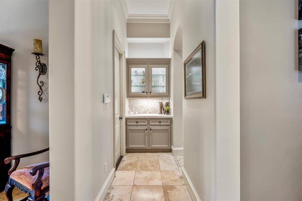 A perfectly placed butler's pantry with in cabinet lighting and herringbone tiled backsplash.