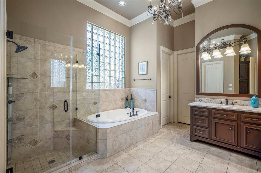 The primary bathroom has ample cabinetry, a soaking tub, dual vanities & dual sinks, glass block window offering natural light above a whirlpool tub, and updated Frameless Separate shower.