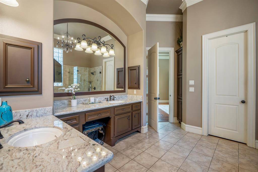 The spa like luxurious en-suite bath offers expansive granite countertops vanities, framed mirrors, custom lighting, and separate step-down shower.
