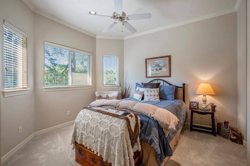 The second bedroom upstairs with lots of windows that stream in natural light to a neutral toned room with plush carpeting and spacious closet.