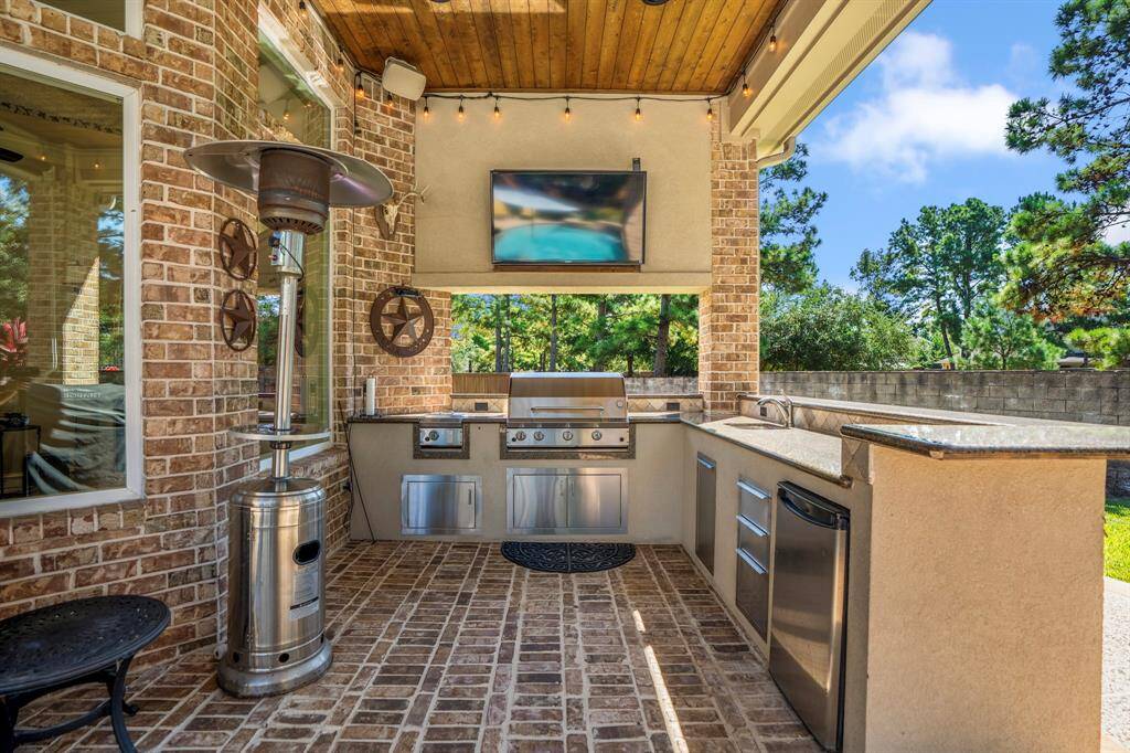 Memories to be made at this full wrap around outdoor bar, with outdoor kitchen featuring grill, bar, dishwasher, and fridge.