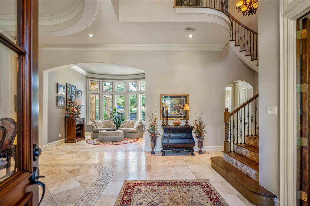 Entering the home you are greeted with a grand entryway featuring custom soaring ceilings and wrought iron sweeping staircase.