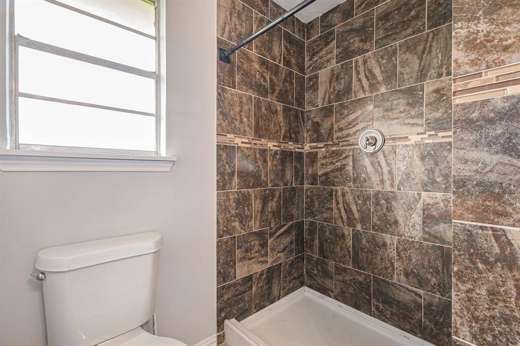This large walk-in shower features warm-toned tile and a solid piece shower  basin.