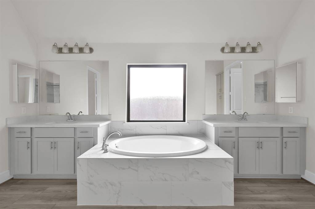 Relax and unwind in the luxurious en suite primary bath that has a soaking garden tub and dual vanities