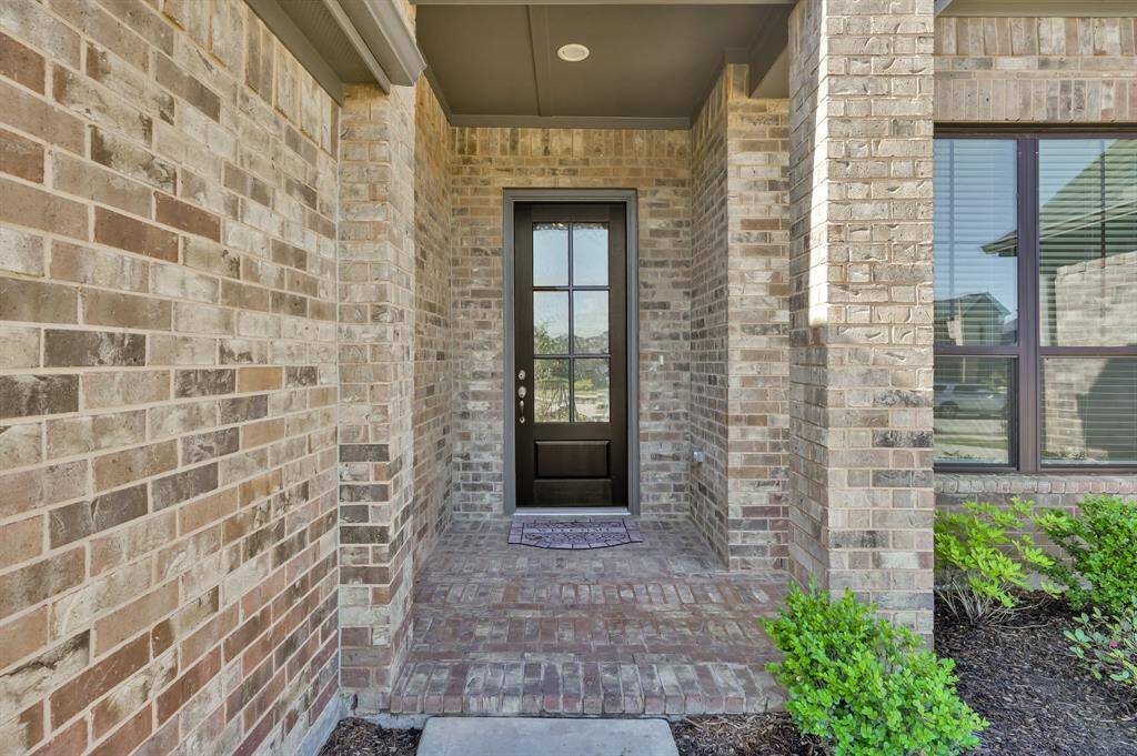 The brick front porch is beautifully accented by a wood and glass door