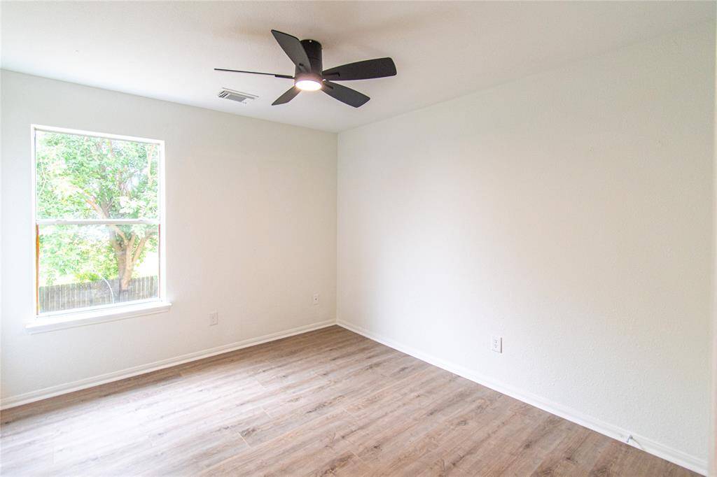 Large window, wood flooring, and a ceiling fan. Ideal for a bedroom or office space.