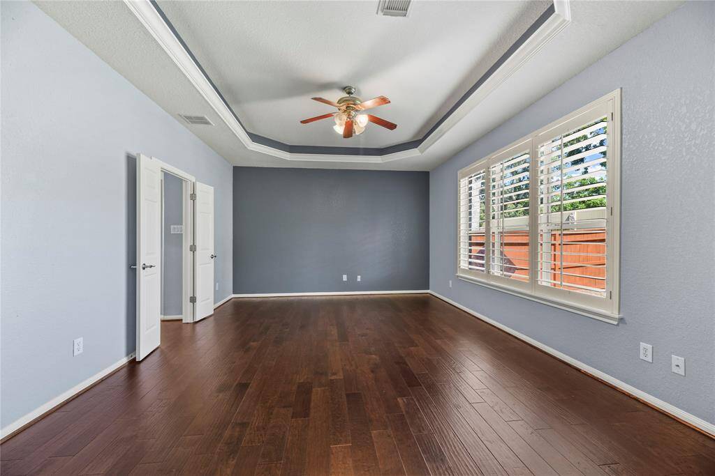 Oversized with high ceilings, the primary bedroom accommodates large furniture, while the wood floors bring forth a cozy and comfortable vibe.