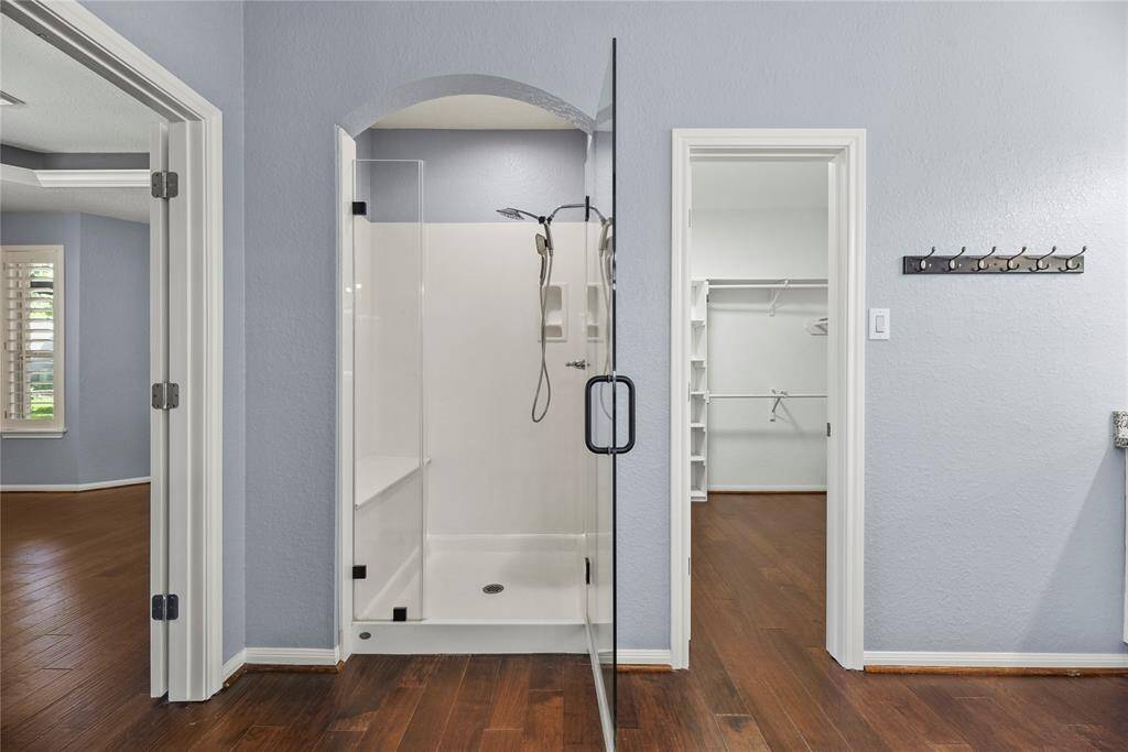 This luxurious primary bathroom shower features a built-in bench, enclosed by a sleek glass door.