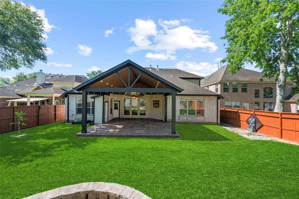 The oversized covered backyard patio offers ample space for relaxing and entertaining in any weather. Its stylish patterned concrete flooring adds a touch of elegance and durability to the outdoor living area.
