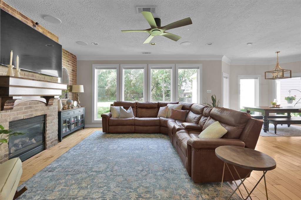 Open and spacious living room with custom brick accent wall, large oversized windows overlooking the back lawn, recessed lighting throughout and already wired for sound with speakers