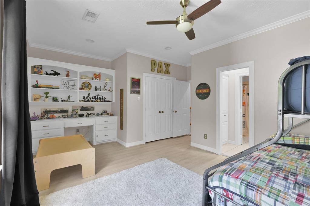 A large secondary bedroom with custom built in shelves and workspace.