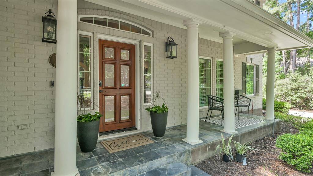 Gorgeous front porch lined with pillars and outfitted with a stunning wooden/glass door