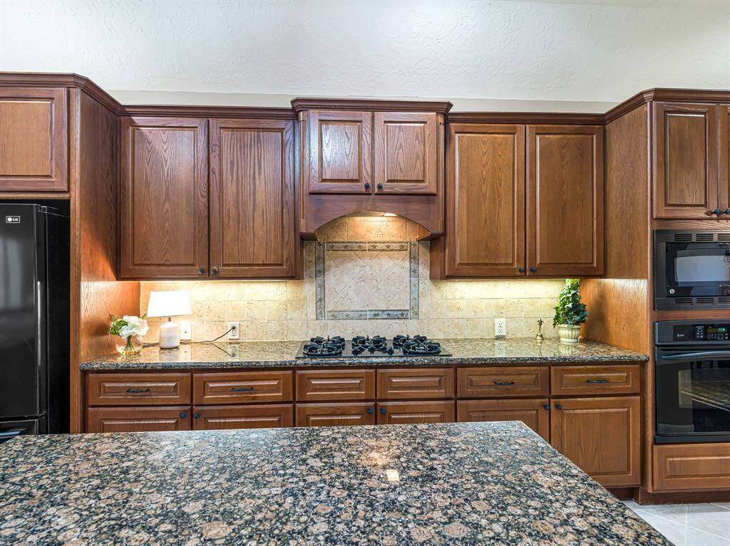 The kitchen is finished with durable 14-inch tile flooring and showcases elegant granite countertops paired with a tumbled stone backsplash, offering timeless style and easy maintenance. Home chefs will appreciate the gas cooktop and the massive walk-in pantry, offering exceptional storage.